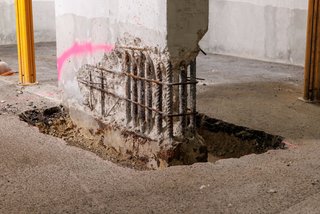 Freigelegter Betonpfeiler mit sichtbarer, korrodierter Bewehrung.